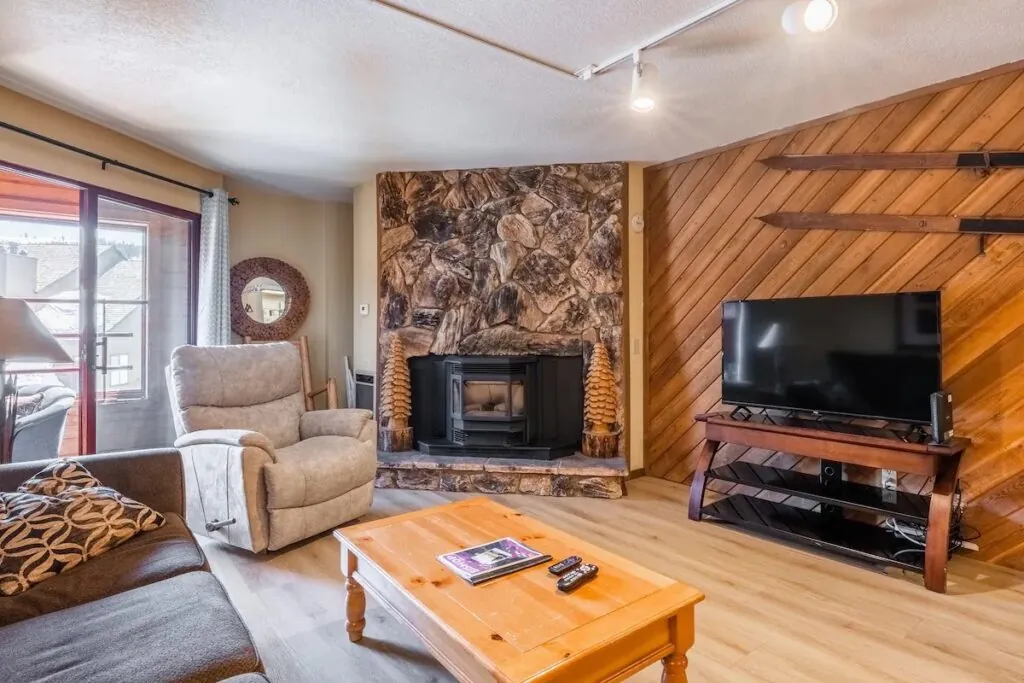 Living room with stone fireplace and TV in the 2-bedroom Aloha Mammoth condo